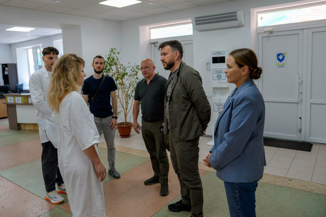 Робочий візит Міністра соціальної політики, сім’ї та єдності Дениса Улютіна та заступника начальника Херсонської ОВА Євгенія Ігнатенка до Херсонської дитячої обласної клінічної лікарні. Посадовці у вестибюлі установи спілкуються з директоркою закладу Інною Холодняк, яка стоїть ліворуч у білому медичному халаті, та іншими медичними працівниками, обговорюючи матеріально-технічне забезпечення та цілодобову роботу колективу з порятунку дітей в умовах постійних російських обстрілів.