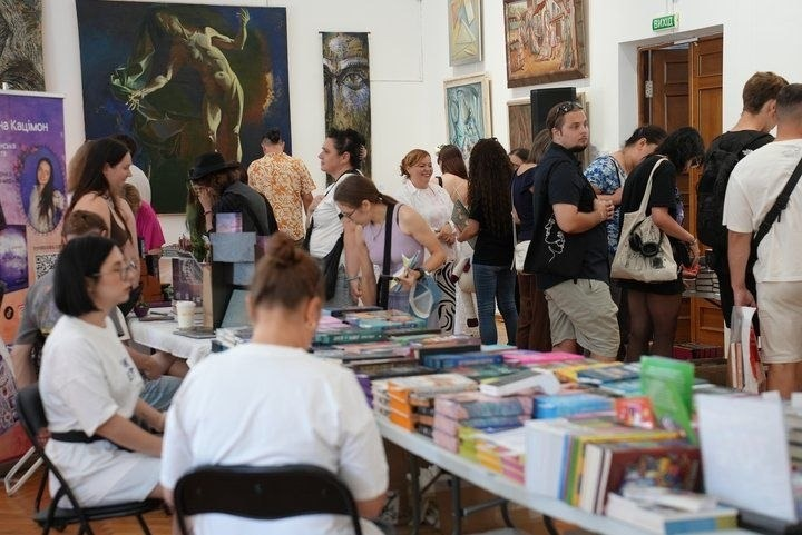 У межах святкових заходів до Дня Незалежності України у Черкасах, організованих за підтримки Чаплинської та Долматівської СВА, переселенці з Херсонщини відвідали літературний фестиваль «Змістовно». На фото зафіксовано атмосферу книжкового ярмарку у великому залі, прикрашеному художніми картинами на стінах. Багаточисельні відвідувачі спілкуються та обирають літературу біля довгих столів, що вщент заповнені різноманітними книжковими новинками, які згодом поповнять «Вільну полицю» хабу для буккросингу.