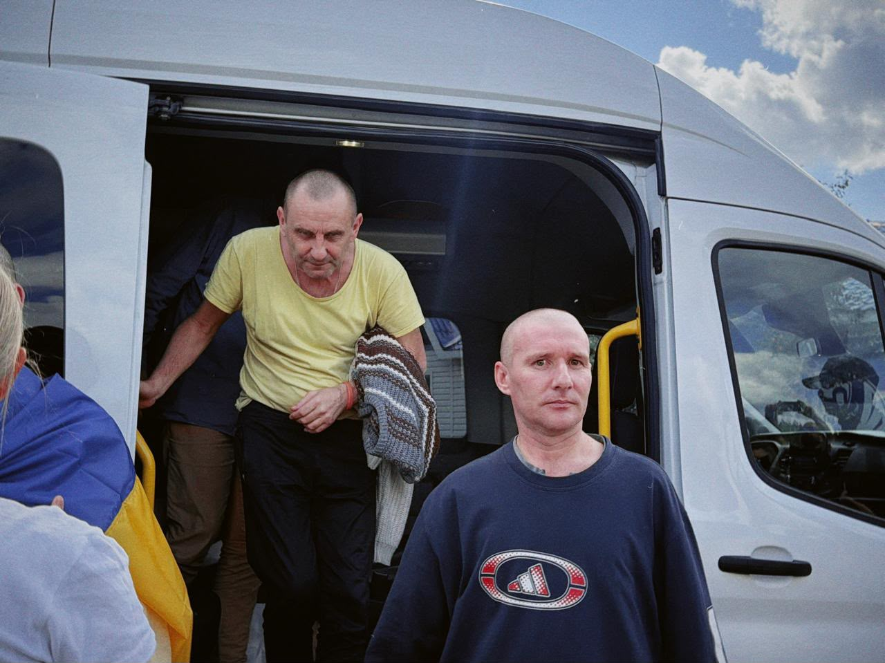 У межах спеціального етапу обміну через територію Білорусі, що відбувся 24 серпня, додому повернулися 10 українських захисників із лав ЗСУ та Нацгвардії, які вважалися зниклими безвісти на Донецькому напрямку. На фото двоє звільнених військовослужбовців виходять із салону білого пасажирського мікроавтобуса на рідну землю, тримаючи свої речі, після тривалого перебування в російській неволі.