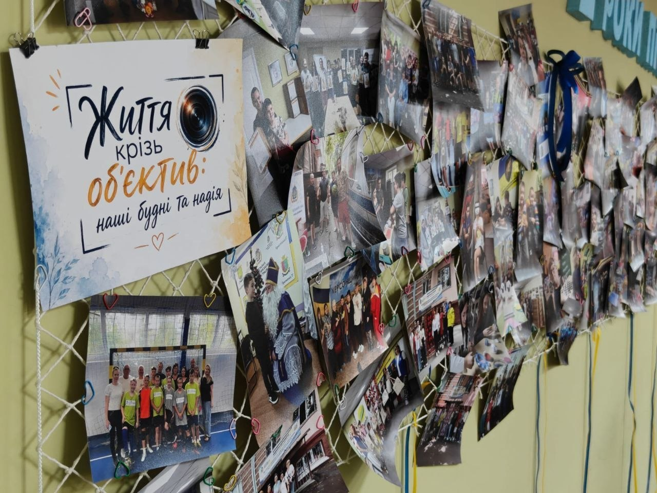 Координаційним центром «Вільні разом» у Дніпрі до Всесвітнього дня фотографії для підтримки ВПО з Херсонщини. На білій декоративній сітці, натягнутій на стіні, скріпками закріплено десятки світлин із буднів та заходів центру за 2 роки його роботи. Ліворуч розміщено головний плакат із назвою виставки, а знизу звисають синьо-жовті стрічки.