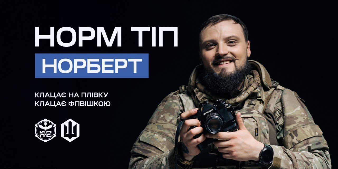 Рекрутингове зображення 20-ї окремої бригади безпілотних систем «К-2» із портретом усміхненого військового з бородою на ім'я Норберт. Боєць у камуфляжній формі тримає в руках плівковий фотоапарат Chinon. На чорному тлі ліворуч розміщено великі написи: «НОРМ ТІП. НОРБЕРТ» та гасло «КЛАЦАЄ НА ПЛІВКУ, КЛАЦАЄ ФПВІШКОЮ». У кутку зображено білі емблеми підрозділів.Супровідний текст описує 4 прості кроки для вступу до лав бригади: перехід на офіційний сайт k-2.army для вибору вакансії, заповнення заявки, проходження співбесіди з рекрутером та прибуття до підрозділу. Кандидатам гарантують службу за фахом, гідне ставлення та надійне забезпечення.
