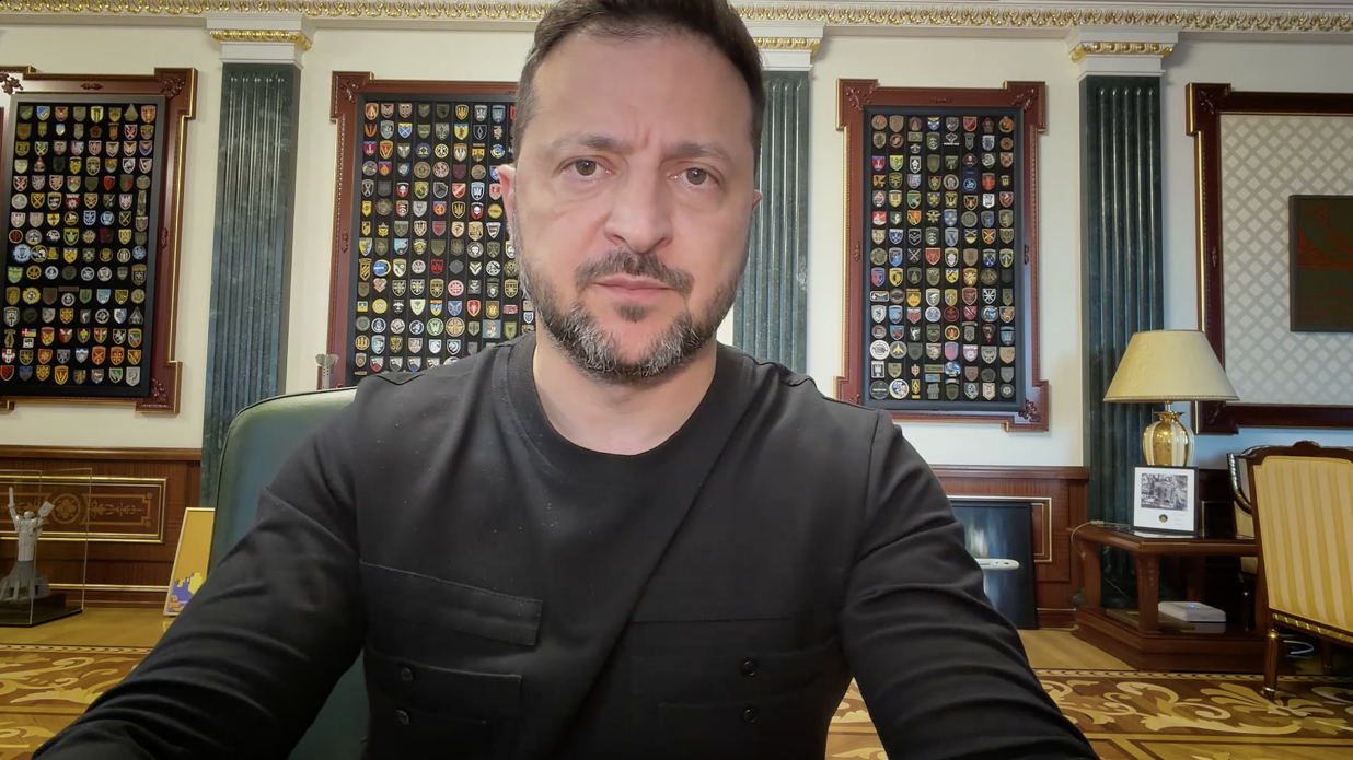 Президент України Володимир Зеленський під час вечірнього відеозвернення від 3 вересня 2026 року. Володимир Зеленський у чорному світшоті зафіксований крупним планом на тлі великих настінних стендів із сотнями військових шевронів сил оборони України. Президент повідомляє про узгодження попередніх дат та підтвердження візиту представників команди Президента США Дональда Трампа — Стіва Віткоффа та Джареда Кушнера — до Києва найближчими днями.