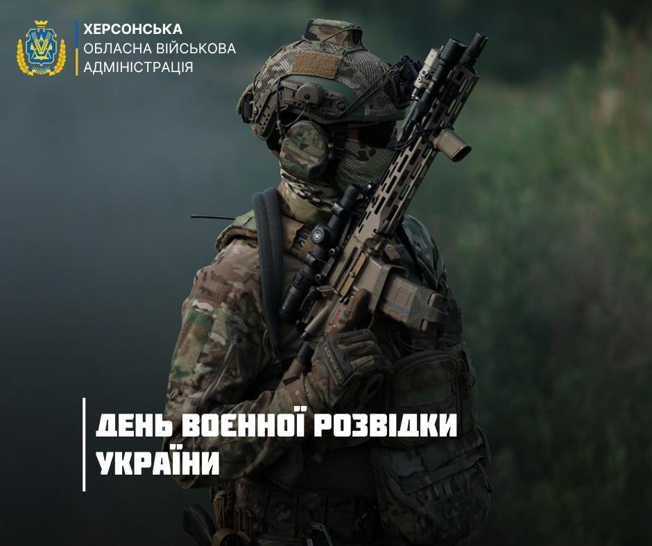 Інформаційний банер Херсонської обласної військової адміністрації до привітання з Днем воєнної розвідки України, що відзначається 7 вересня. На зображенні у профіль показано українського розвідника в камуфляжній формі мультикам, тактичному шоломі з маскувальним кавером, захисних окулярах, навушниках та балаклаві, яка повністю закриває обличчя відвідувача. Боєць тримає в руках сучасну автоматичну гвинтівку з оптичним прицілом та додатковим тактичним спорядженням. Фотографія виконана у стриманих темно-зелених та захисних тонах із розмитим лісовим тлом, що підкреслює специфіку та таємність роботи розвідників на передовій і в тилу противника. У верхньому лівому кутку розміщено офіційний жовто-блакитний герб області та підпис Херсонська обласна військова адміністрація. У нижній лівій частині великими білими літерами на тлі вертикальної лінії нанесено вітальний напис День воєнної розвідки України.
