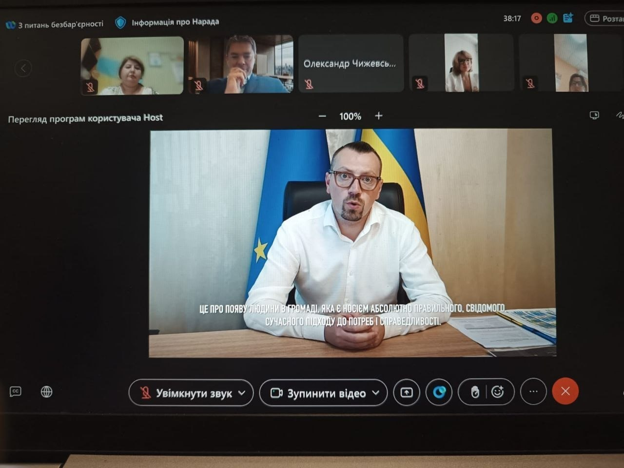 Скріншот першої всеукраїнської онлайн-зустрічі уповноважених з питань безбар’єрності, організатором якої виступило Міністерство з відновлення, інфраструктури та транспорту України. На великому центральному вікні екрана виступає спікер в окулярах та білій сорочці, який сидить за робочим столом на тлі державного прапора України та прапора Європейського Союзу. Під ним виведено субтитри з його словами: це про появу людини в громаді, яка є носієм абсолютно правильного, свідомого, сучасного підходу до потреб і справедливості. У верхній панелі екрана відображаються вікна з іншими учасниками наради, серед яких представники управління містобудування та архітектури Херсонської ОДА й громад області. Захід об’єднав близько 1300 фахівців для обговорення людиноцентричного підходу, створення безбар’єрного середовища, розроблення місцевих планів заходів та врахування принципів доступності на етапі планування і відбудови територій.