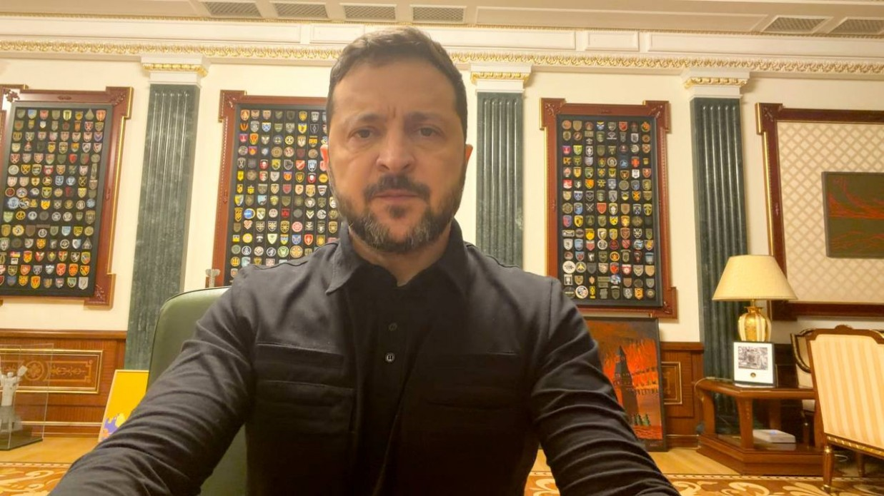 Президент України Володимир Зеленський записав офіційне звернення з робочого кабінету, заявивши, що для забезпечення реальної готовності Росії припинити війну на знищення життя Україна зробить свої деескалаційні кроки. Він перебуває по центру кадру в чорній тактичній сорочці-поло та зосереджено дивиться в камеру. На задньому плані кабінету зі світлими стінами та зеленими колонами розташована стіна шевронів, де у трьох великих дерев'яних рамах виставлено сотні нашивок військових підрозділів і бригад ЗСУ. Праворуч на столику горить лампа під бежевим абажуром, а поруч на підлозі стоїть картина із палаючим Кремлем.