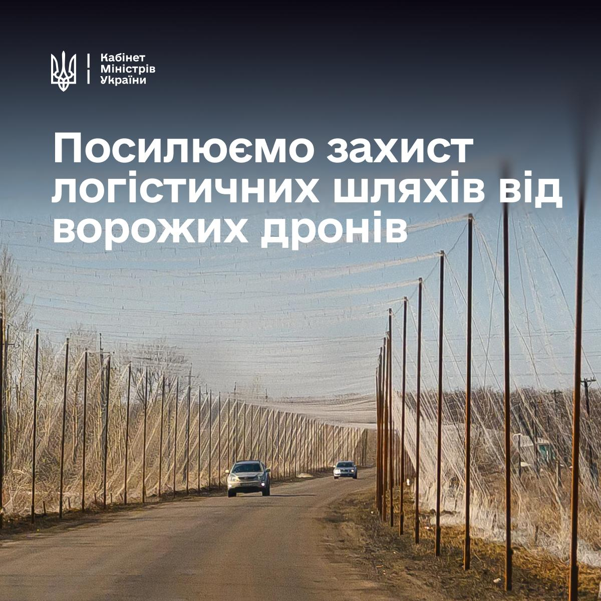 Інформаційний банер Кабінету Міністрів України повідомляє, що Уряд виділить 789 мільйонів гривень з резервного фонду на антидроновий захист логістичних шляхів. На зображенні показано захисну сітку від ворожих дронів, натягнуту над асфальтованою дорогою на високих опорах, утворюючи безпечний коридор для автомобілів на тлі дерев і неба. У верхній частині плаката ліворуч розміщено офіційний логотип із тризубом та написом «Кабінет Міністрів України», а по центру великими білими літерами нанесено заголовок «Посилюємо захист логістичних шляхів від ворожих дронів» для прифронтових регіонів, зокрема Херсонщини.