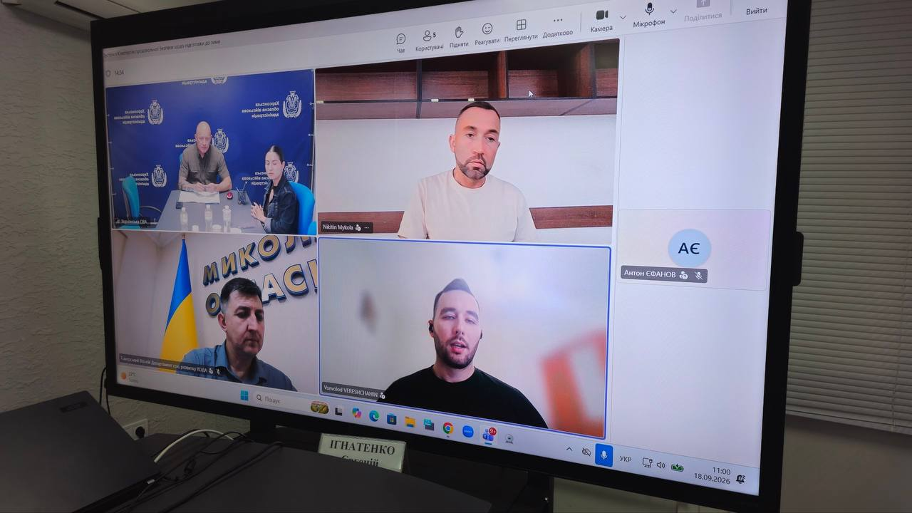 Великий настінний монітор відображає вікно онлайн-наради в Microsoft Teams, де в межах п'яти віконців учасників проходить робоча зустріч заступника начальника Херсонської ОВА Євгенія Ігнатенка з представниками Всесвітньої продовольчої програми ООН (WFP) щодо підтримки жителів області в осінньо-зимовий період. У лівому верхньому кутку за великим столом на тлі синього банера ХОДА спільно сидять заступник начальника Херсонської ОВА Євгеній Ігнатенко та начальниця управління міжнародного співробітництва та залучення інвестицій ХОДА Марія Богодухова. По центру вгорі відображається Координатор Кластера продовольчої безпеки та життєзабезпечення ООН у Херсонській області Микола Нікітін (Nikitin Mykola), праворуч розташоване віконце з ініціалами заступника начальника Херсонської МВА Антона Єфанова, а у лівому нижньому кутку на тлі державного прапора сидить заступник директора Департаменту соціального розвитку ХОДА Віталій Гомерський. Знизу по центру виступає Радник Кластера Всеволод Верещагін (Vsevolod VERESHCHAGIN) під час обговорення пріоритетів підготовки Херсонщини до зими 2026–2027 років для забезпечення продовольством понад 57 тисяч мешканців області.