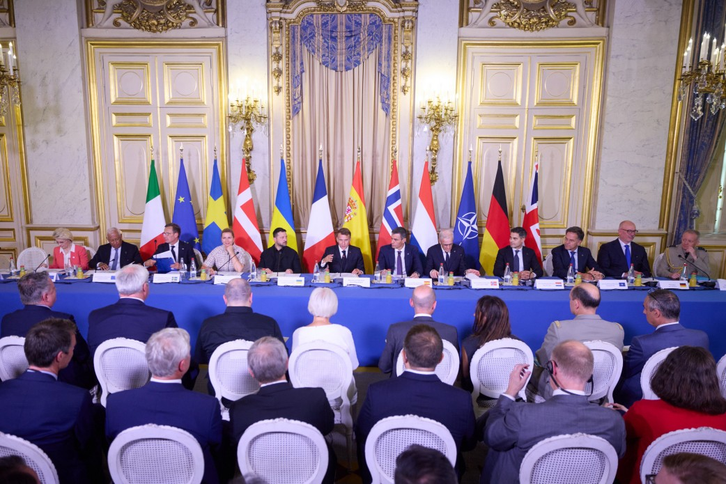 Глави держав та урядів країн-засновниць на чолі з Президентом України Володимиром Зеленським та Президентом Франції Емманюелем Макроном сидять за довгим синім столом у Парижі під час презентації Антибалістичної програми FREYJA та підписання Спільної декларації про створення Інтегрованої Антибалістичної коаліції. По центру засідання поруч із французьким лідером сидить Володимир Зеленський у чорній сорочці, а з обох боків розмістилися Прем’єр-міністерка Данії Метте Фредеріксен, Премʼєр-міністр Іспанії Педро Санчес, Прем’єр-міністр Нідерландів Роб Єттен, Прем’єр-міністр Норвегії Йонас Гар Стере, Прем’єр-міністр Швеції Ульф Крістерссон, Генеральний секретар НАТО Марк Рютте, Президентка Єврокомісії Урсула фон дер Ляєн та інші високопосадовці. Позаду лідерів у ряд виставлено державні прапори Італії, ЄС, Швеції, Данії, України, Франції, Іспанії, Норвегії, Нідерландів, НАТО, Німеччини та Великої Британії, а на передньому плані на білих стільцях сидить аудиторія, що ілюструє процес об'єднання зусиль для створення європейської системи захисту від балістики.