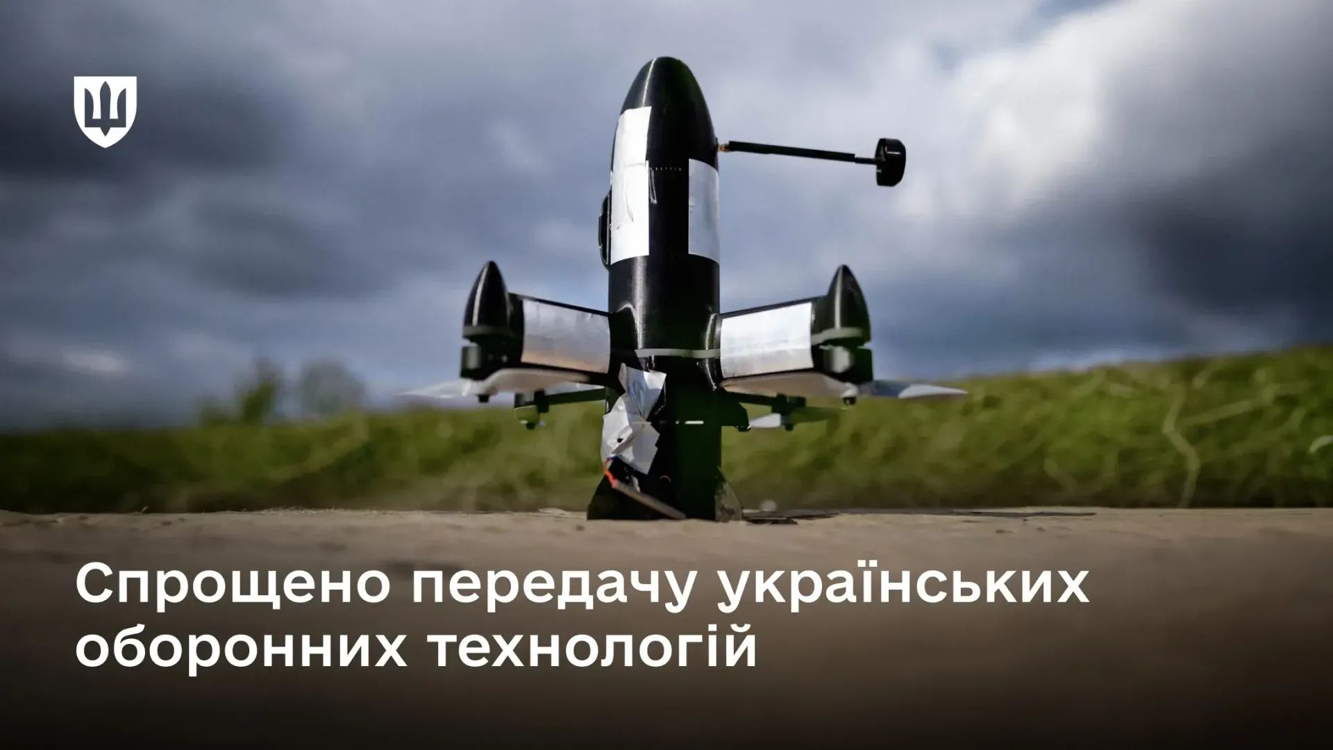 Офіційний інформаційний банер із заголовком про спрощення передачі технологій, на якому зображено інноваційний український безпілотник вертикального зльоту та посадки (VTOL), встановлений на бетонній поверхні на тлі поля й хмарного неба. Новітній дрон має чорний обтічний корпус та чотири розкладні крила-модулі зі сріблястими металевими елементами. У лівому верхньому кутку банера розміщено білий Малий Державний Герб України, а внизу нанесено великий напис «Спрощено передачу українських оборонних технологій», що ілюструє нову постанову Кабміну, яка скорочує до 30 днів процедуру Держекспортконтролю для передачі озброєння та конструкторської документації партнерам у межах формату Drone Deal.