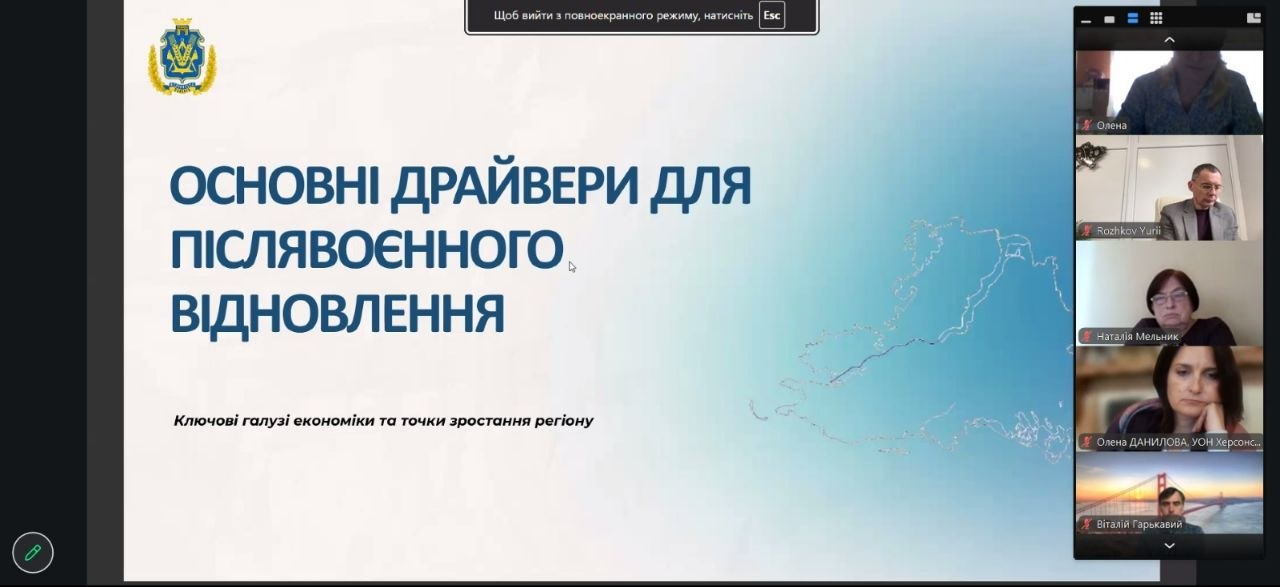 На екрані в інтерфейсі програми Zoom Workplace зафіксовано демонстрацію фінальної частини презентації моделі повоєнного відновлення регіону під час онлайн-засідання регіональної ради професійної освіти при Херсонській ОВА. Головну частину монітора займає слайд із офіційним гербом Херсонської області та великим синім заголовком «ОСНОВНІ ДРАЙВЕРИ ДЛЯ ПІСЛЯВОЄННОГО ВІДНОВЛЕННЯ» під яким нанесено підзаголовок «Ключові галузі економіки та точки зростання регіону» на тлі контурної карти Херсонщини. У вертикальному стовпчику учасників відеодзвінка праворуч згори донизу розташовані віконця посадовців та підприємців: Олена, комерційний директор ПП «Оригінал Авто» Юрій Рожков, Наталія Мельник, начальник управління освіти і науки Херсонської ОДА Олена Данилова та Віталій Гарькавий, що ілюструє виступ директора Департаменту розвитку економіки ХОДА Артема Мішина про збереження людського капіталу як ключового чинника реалізації економічних планів.