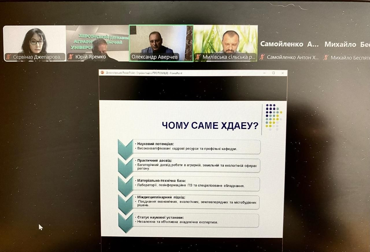 На екрані монітора в інтерфейсі онлайн-конференції зафіксовано демонстрацію слайда презентації «ЧОМУ САМЕ ХДАЕУ?» під час робочої наради щодо підтримки деокупованих громад у сфері комплексного просторового планування під головуванням заступника начальника ХОВА Антона Самойленка. У верхньому ряду учасників відеодзвінка розташовані віконця посадовців та науковців: начальник управління містобудування та архітектури Херсонської ОДА Сервіназ Джепарова, Юрій Яремко, Олександр Аверчев, представник Милівської сільської військової адміністрації (СВА), а також текстові плашки Антона Самойленка та Михайла Беспятого. На головному слайді деталізовано п'ять ключових переваг залучення університету до відбудови регіону через платформу Living Lab: науковий потенціал (кадри й кафедри), практичний досвід (в аграрній, земельній та екологічній сферах), матеріально-технічна база (лабораторії, геоінформаційне ПЗ), міждисциплінарний підхід та статус наукової установи для проведення прикладних досліджень і точних кадастрових розрахунків на місцях.