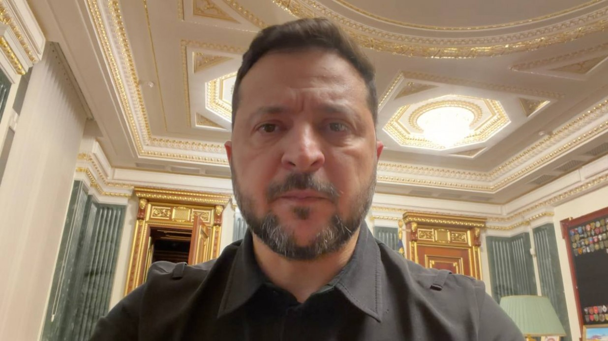 Президент України Володимир Зеленський у чорній тактичній сорочці виступає під час щоденного вечірнього звернення, зазначаючи, що вже визначені конкретні типи перехоплювачів, які можуть стати основним засобом захисту країни від повітряних загроз. Глава держави зафіксований крупним планом на тлі розкішного класичного інтер'єру кабінету в Офісі Президента України з високою білою стелею, прикрашеною витонченою золотою ліпниною, масивними позолоченими дверима та зеленими мармуровими колонами, що ілюструє офіційну заяву лідера щодо модернізації системи протиповітряної оборони, нарощування військово-технічного потенціалу та посилення безпеки українського неба.