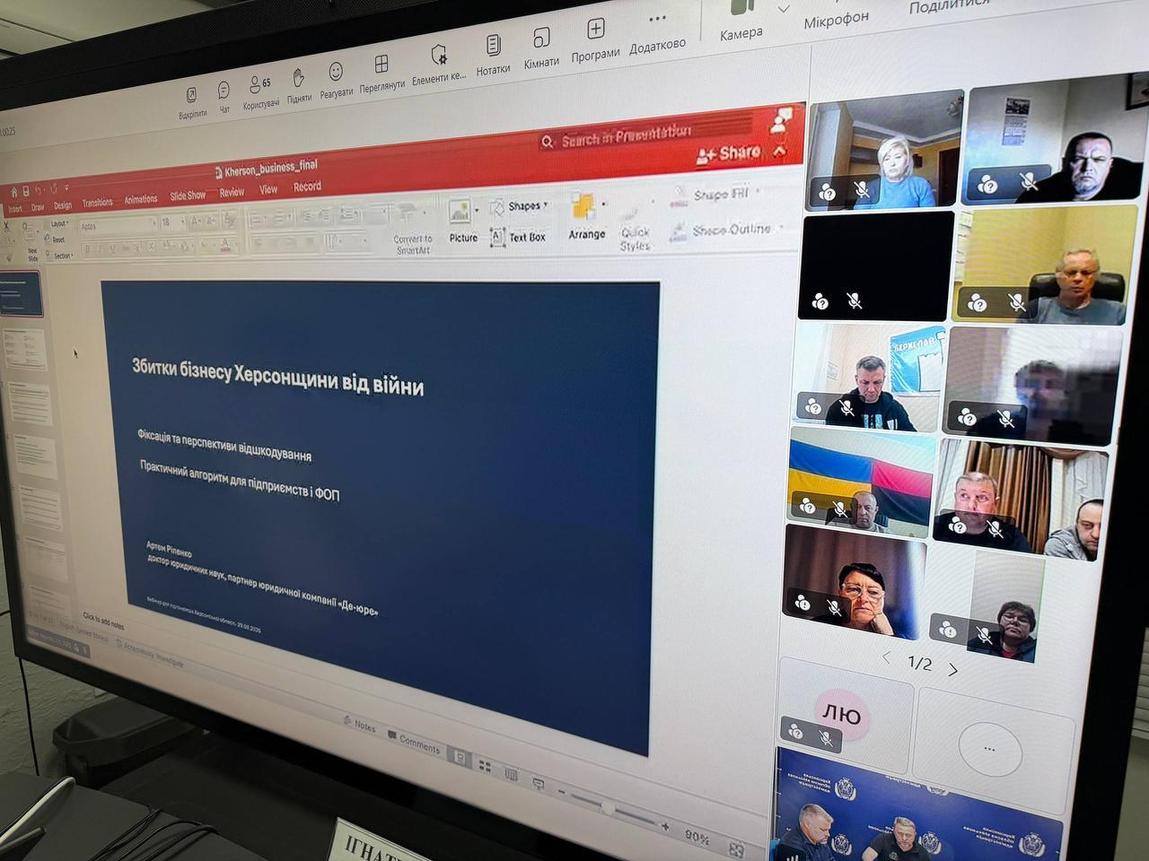 Великий монітор відображає трансляцію онлайн-зустрічі «Діалог влади та бізнесу» у програмі Microsoft Teams, де на головному екрані відкрито слайд презентації юридичної компанії «Де-юре» під назвою «Збитки бізнесу Херсонщини від війни». На червоно-білому титульному аркуші виведено підзаголовки «Фіксація та перспективи відшкодування», «Практичний алгоритм для підприємств і ФОП», а також зазначено спікера — доктора юридичних наук Артема Ріпенка. Праворуч у вертикальному стовпчику вікон онлайн-зв'язку транслюються інші учасники наради, серед яких у нижньому віконці видно засідання першого заступника начальника Херсонської ОВА Дмитра Бутрія, біля якого сидить директор Департаменту розвитку економіки Херсонської ОДА Артем Мішин, а вище розташовані кадри підключень представників підприємств та податкової служби, що ілюструє дистанційне обговорення механізмів фіксації пошкоджень майна та податкових пільг для бізнесу регіону.