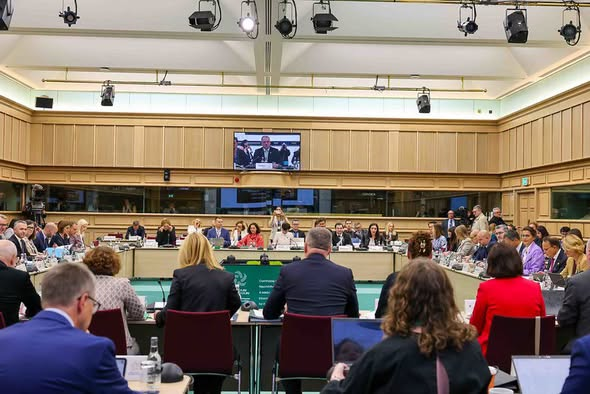 Чисельні представники європейських дипломатичних кіл та країн-кандидатів заповнюють простору залу за підковоподібним великим столом під час неформального засідання Ради ЄС із загальних справ (GAC) у Дубліні. На передньому плані спиною до камери зафіксовано учасників зустрічі, які працюють за ноутбуками та вивчають документи, а у центрі зали розташовано стіл президії із зеленою інформаційною панеллю. На підвісному центральному екрані на задньому плані транслюється великий план спікера, що ілюструє доповідь віцепрем’єр-міністра з питань європейської та євроатлантичної інтеграції Всеволода Ченцова про готовність України до паралельного руху трьома треками євроінтеграції: переговорами, реформами та практичною секторальною інтеграцією до внутрішнього ринку ЄС.