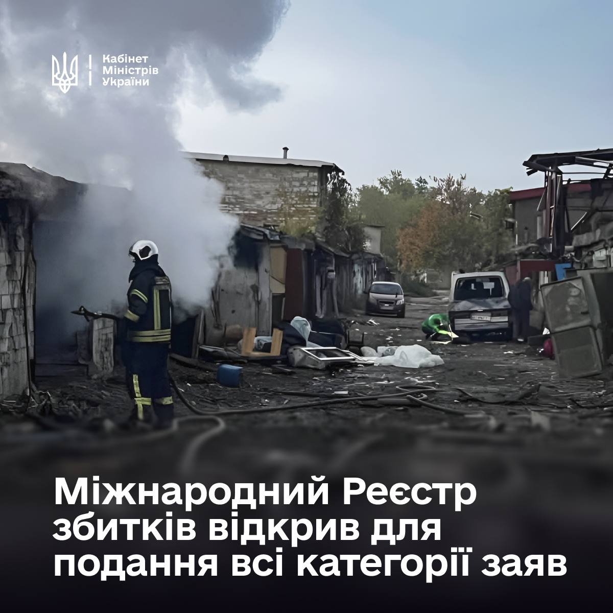 Рятувальник Державної служби з надзвичайних ситуацій у захисному спорядженні та шоломі гасить пожежу серед зруйнованих обстрілами приватних гаражів і будівель, з яких валить густий білий дим. Навколо пошкоджених споруд зафіксовано сильні руйнування, розкидані уламки будівельних матеріалів та речі. На розмитому задньому плані видно вцілілий білий мікроавтобус та пошкоджені металеві конструкції. У лівому верхньому кутку зображення нанесено білий малий Державний Герб України та напис «Кабінет Міністрів України», а в нижній частині великими білими літерами розміщено головний заголовок: «Міжнародний Реєстр збитків відкрив для подання всі категорії заяв». Кадр ілюструє фіксацію наслідків російської агресії, за які передбачено отримання компенсацій через портал «Дія».