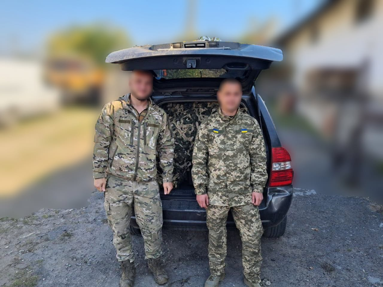 Двоє українських військовослужбовців у камуфляжній формі позують на тлі відкритого багажника позашляховика, який повністю заповнений маскувальними сітками. Захисники стоять поруч на ґрунтовій дорозі, а завантажене у машину покриття зеленого, чорного та бежевого кольорів виготовлене та передане волонтерками Бериславської громади. Світлина ілюструє процес доставки чергової партії допомоги на передову для системного забезпечення Сил оборони та надійного укриття бліндажів, позицій та техніки від безпілотників ворога.