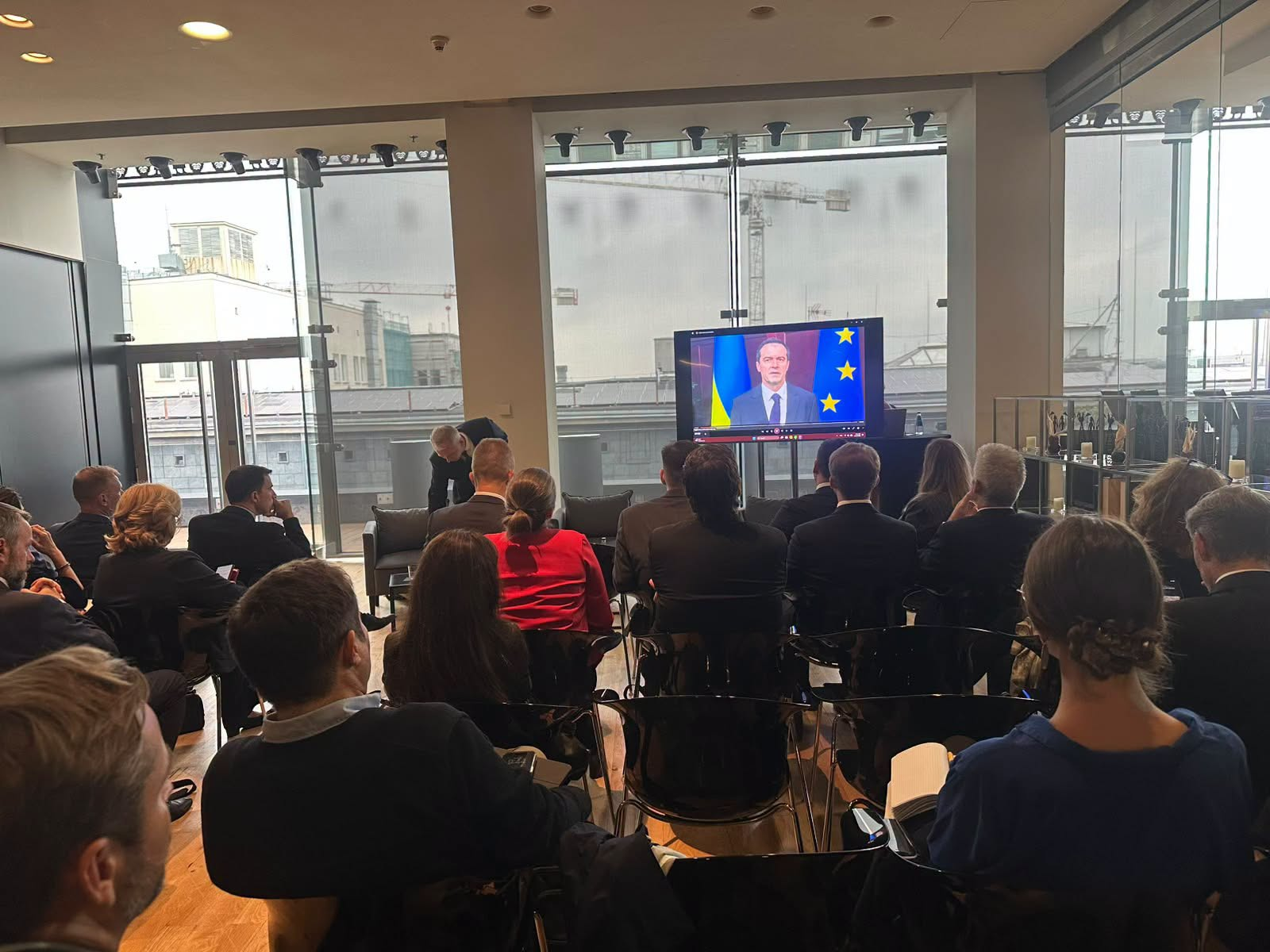 Учасники конференції Europe Future Forum 2026 у Варшаві дивляться онлайн-виступ Віцепрем’єр-міністра Всеволода Ченцова, який транслюється на великому екрані по центру зали. На моніторі урядовець зафіксований на тлі прапорів України та ЄС, а численна аудиторія в ділових костюмах сидить на чорних стільцях у просторому приміщенні з панорамними вікнами та видом на місто під сірим небом. Під час звернення «Making Europe Greater and Stronger Together» Всеволод Ченцов наголосив, що розширення ЄС посилить Європу, а Україна зробить вагомий внесок у безпеку й економічну стійкість. Він підкреслив, що фінансовий тягар агресії має нести росія, та закликав партнерів уже зараз планувати спільне економічне майбутнє, впроваджувати реформи й залучати інвестиції.