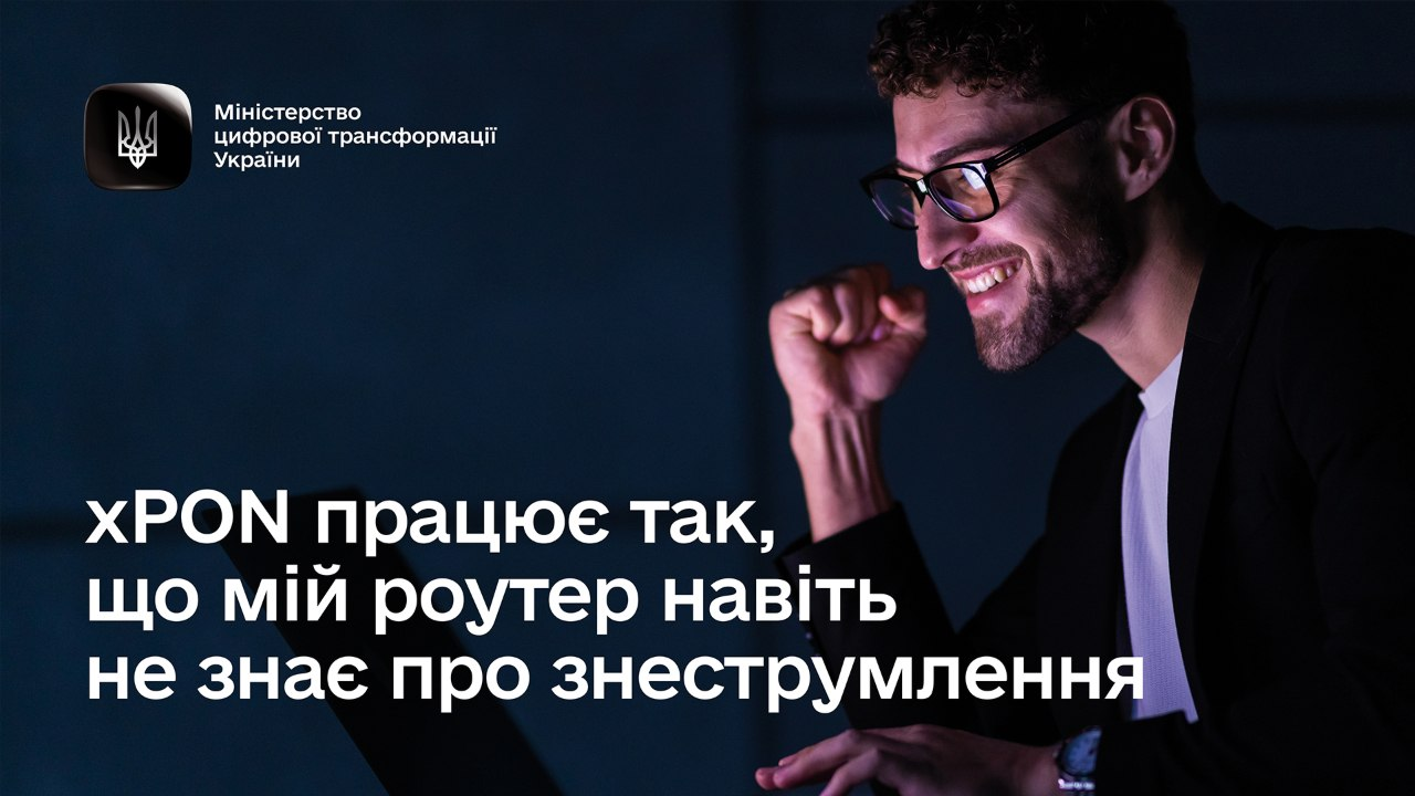 На банері від Міністерства цифрової трансформації України зображено усміхненого молодого чоловіка в окулярах та чорному піджаці, який радісно стискає кулак, дивлячись у свій ноутбук у темній кімнаті. У лівому верхньому кутку розміщено чорний квадратний логотип відомства з державним гербом (Тризубом) та білим написом «Міністерство цифрової трансформації України». У нижній частині зображення великими білими літерами нанесено текст: «xPON працює так, що мій роутер навіть не знає про знеструмлення».