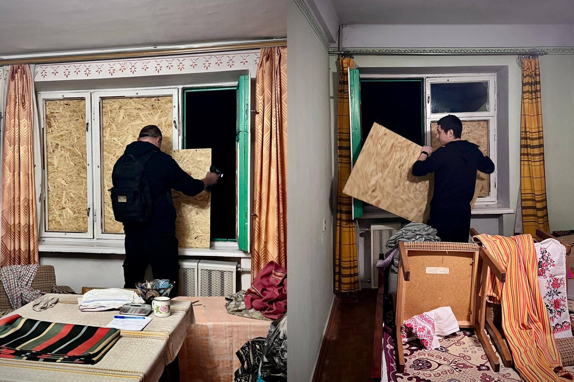 Два кадри, що ілюструють відновлювальні роботи в приміщенні після пошкоджень: чоловік у чорному одязі забиває вікна фанерою (OSB плитами) зсередини кімнати, щоб закрити отвори, що виходять на темну вулицю. На передньому плані видно предмети побуту та меблі.