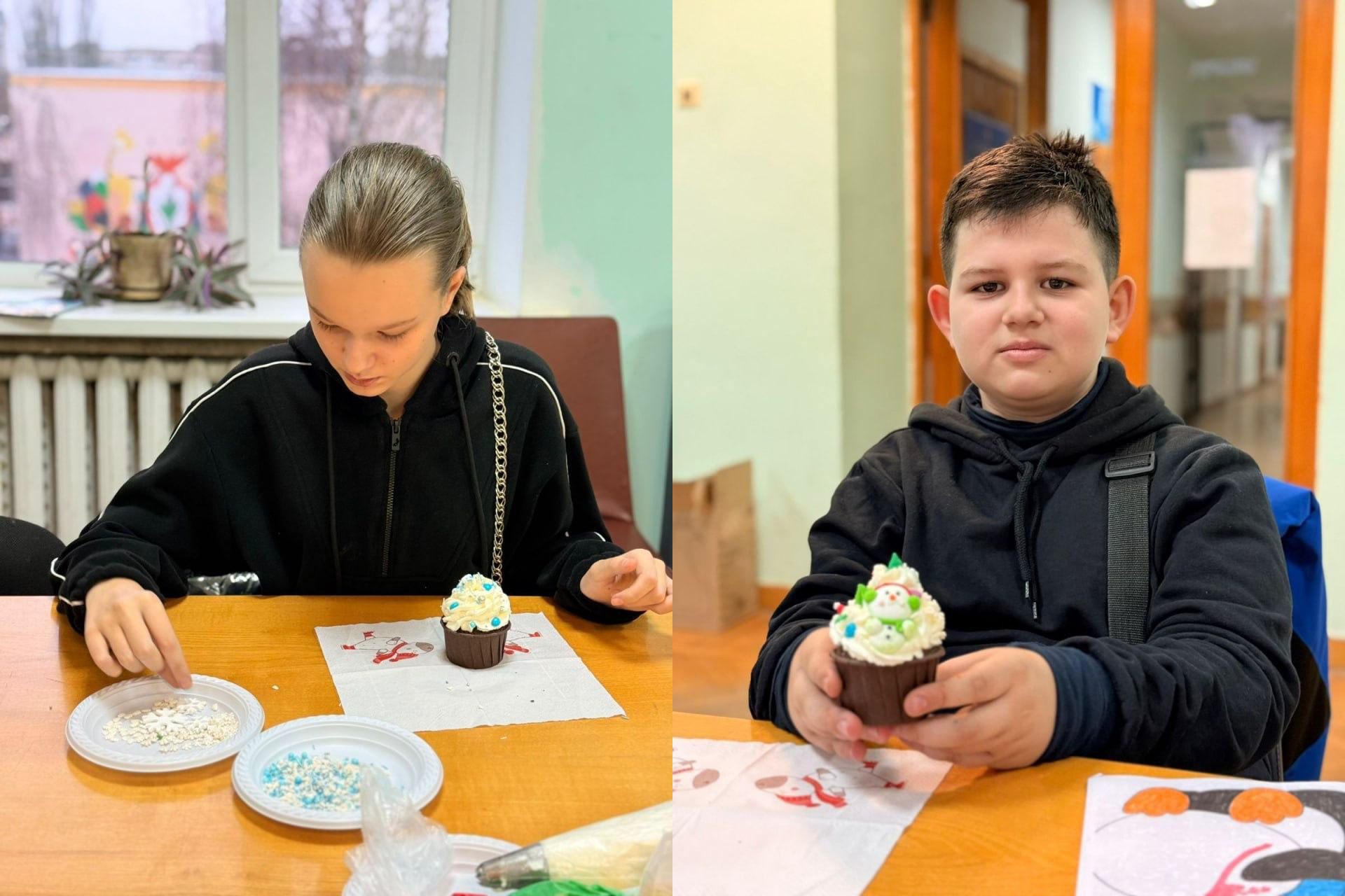 Дівчинка та хлопчик прикрашають кекси святковим кремом і посипкою, сидячи за столом.