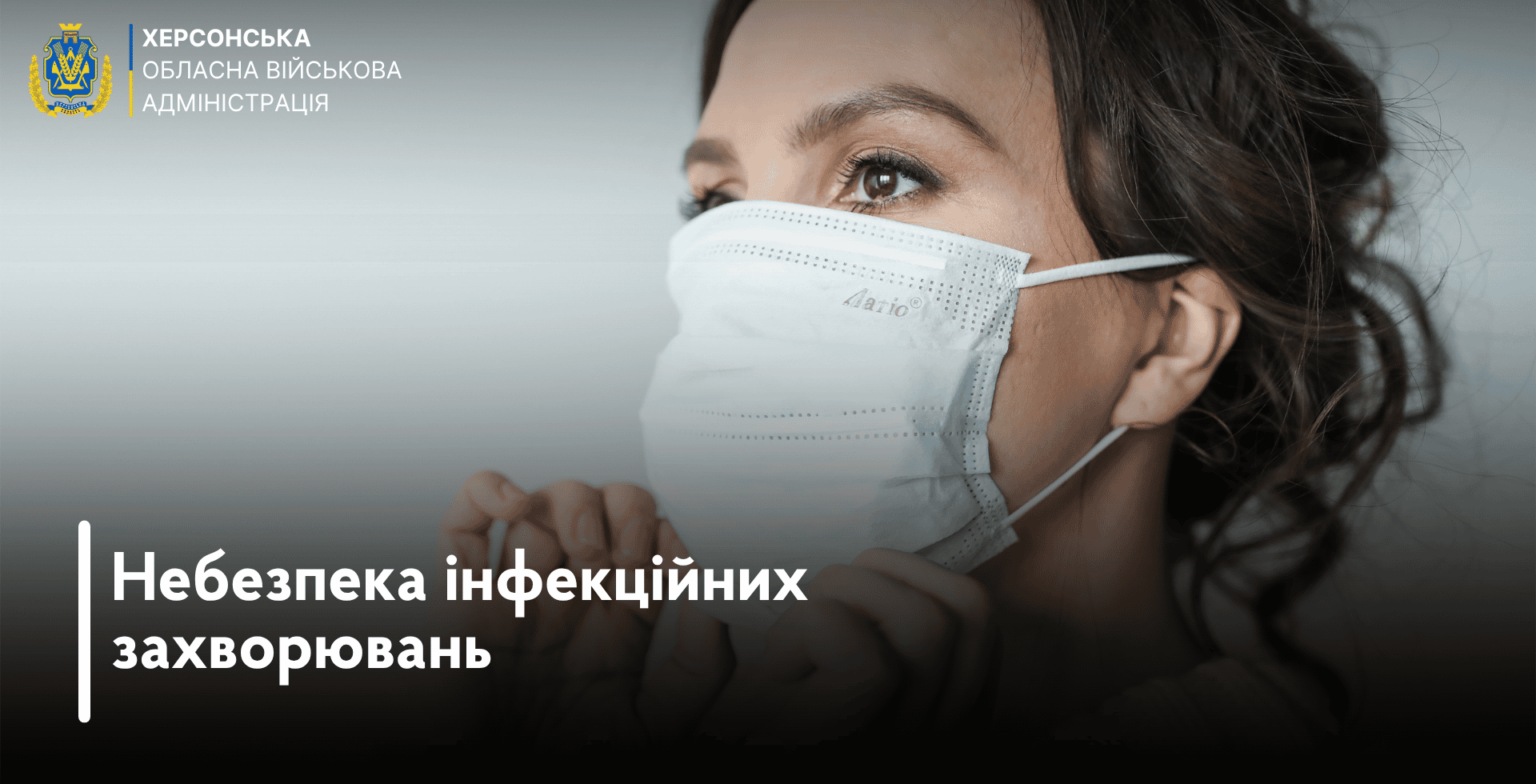 Інформаційно-просвітницький банер Херсонської обласної військової адміністрації, присвячений темі охорони здоров'я. У лівому верхньому кутку зображено кольоровий герб Херсонської області та офіційний текстовий напис у три рядки: «ХЕРСОНСЬКА ОБЛАСНА ВІЙСЬКОВА АДМІНІСТРАЦІЯ». Візуальну основу кадру становить велике фото жінки у напівпрофіль на світло-сірому нейтральному тлі. Вона одягає або поправляє руками білу одноразову медичну маску, що закриває ніс та рот. На самій масці помітне невелике тиснення з назвою бренду «Aario». Погляд жінки спрямований ліворуч і вгору. Нижня частина банера затемнена плавним чорним градієнтом. Поверх нього у лівому кутку нанесено великий жирний заголовок білого кольору, який зліва виділений вертикальною білою лінією: «Небезпека інфекційних захворювань».