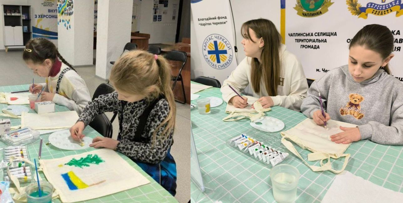 Колаж із двох фотографій, що демонструють процес майстер-класу для дітей. На знімках дівчатка зосереджено малюють на світлих екосумках, використовуючи пензлі та різнокольорові фарби. На одній із сумок уже видно малюнок — зелену ялинку над синьо-жовтим прапором. На столі, застеленому зеленою скатертиною, розкладені палітри, склянки з водою та набори тюбиків із фарбою. На задньому плані одного з фото видно інформаційний банер територіальної громади.