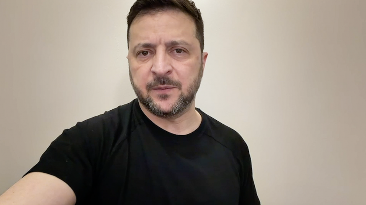 Чоловік середнього віку з короткою темною борідкою та зосередженим поглядом, одягнений у чорну футболку, знятий крупним планом на фоні світлої однотонної стіни.