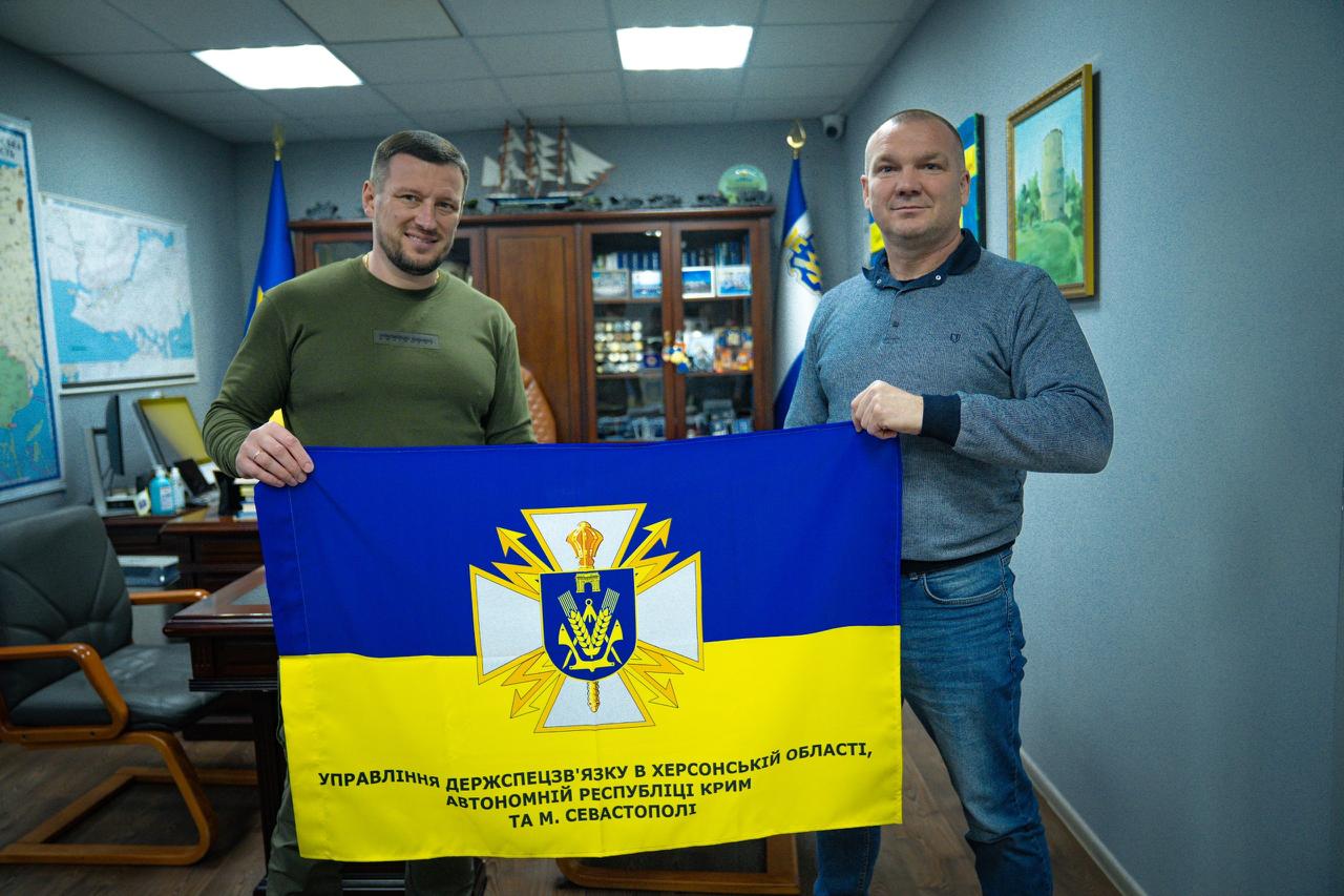 Олександр Прокудін та Дмитро Зорик у кабінеті спільно тримають офіційний прапор Управління Держспецзв’язку в Херсонській області, АР Крим та м. Севастополі після підписання меморандуму про співпрацю.