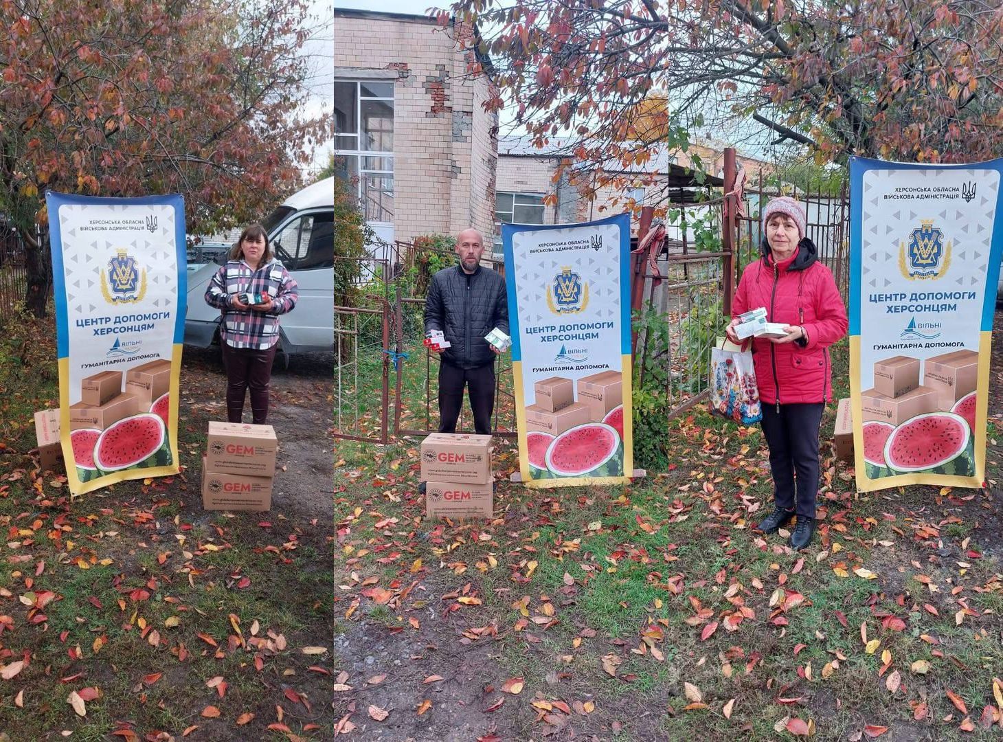 Сцена видачі гуманітарної допомоги восени. На трав'янистому ґрунті біля цегляної будівлі та мікроавтобуса стоять двоє жінок і чоловік, тримаючи невеликі пакунки. За ними розташовані три вертикальні банери «Центр допомоги херсонцям» від Херсонської обласної військової адміністрації, прикрашені зображеннями коробок та скибок кавунів, що символізують регіон. Біля ніг видно стопки картонних коробок з написом GEM.