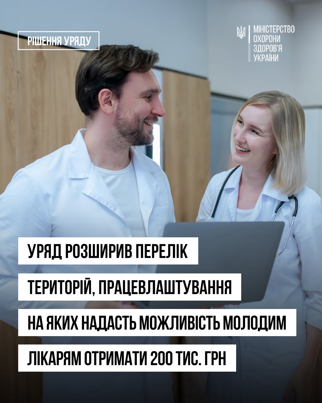 Інформаційний банер Міністерства охорони здоров'я України, виконаний на основі світлої фотографії в медичному закладі. У верхньому лівому кутку в білій контурній рамці нанесено рубрику: «РІШЕННЯ УРЯДУ». У верхньому правому кутку розміщено офіційний білий логотип — малий Державний Герб України (Тризуб) та напис: «МІНІСТЕРСТВО ОХОРОНИ ЗДОРОВ'Я УКРАЇНИ». На фотографії зображені двоє усміхнених медичних працівників — чоловік та жінка у білих лікарських халатах. Жінка-лікар має стетоскоп на шиї, тримає в руках відкритий сірий ноутбук і дивиться на свого колегу. Чоловік-лікар дивиться на неї у відповідь. Вони стоять у приміщенні на тлі дерев'яних меблів. Нижню частину банера займає великий чотирирядковий напис чорними літерами на суцільних білих горизонтальних плашках: «УРЯД РОЗШИРИВ ПЕРЕЛІК» «ТЕРИТОРІЙ, ПРАЦЕВЛАШТУВАННЯ» «НА ЯКИХ НАДАСТЬ МОЖЛИВІСТЬ МОЛОДИМ» «ЛІКАРЯМ ОТРИМАТИ 200 ТИС. ГРН»