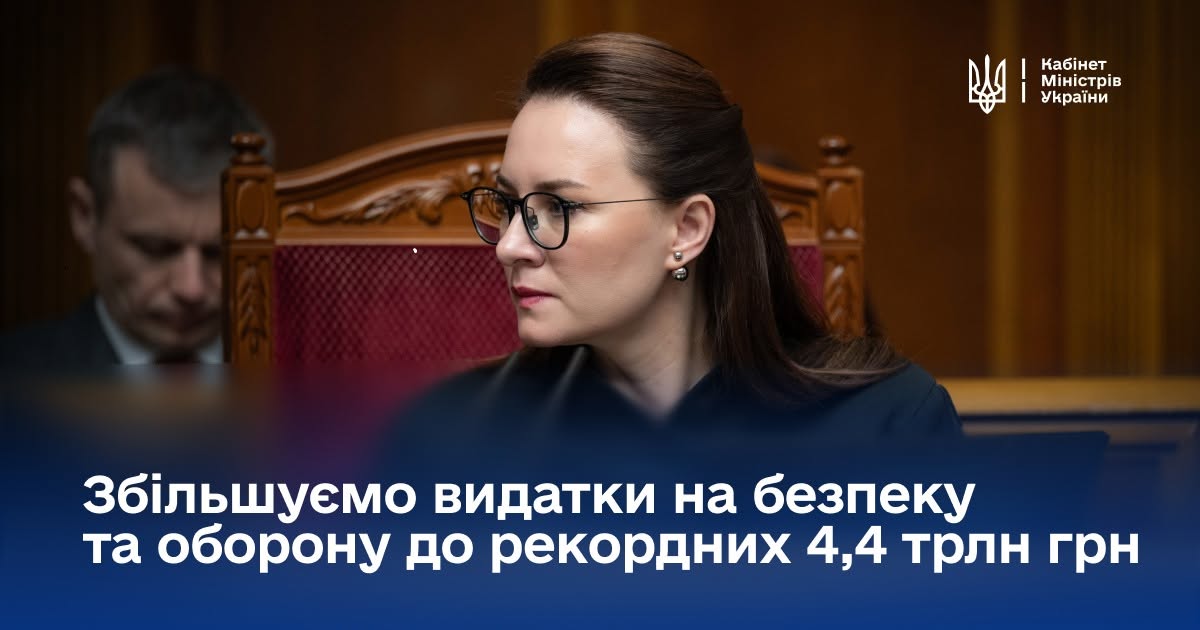 Інформаційний банер Кабінету Міністрів України з офіційним повідомленням про фінансування оборонного сектору.  У правому верхньому кутку розміщено малий Державний Герб України (Тризуб) білого кольору та дворядковий текстовий напис: «Кабінет Міністрів України».  Головним елементом зображення є фотографія Першої віцепрем'єр-міністерки — Міністерки економіки України Юлії Свириденко. Вона зафіксована у профіль, дивиться ліворуч, одягнена в темний офіційний одяг, носить окуляри в чорній оправі та сережки-кульки. Міністерка сидіти у залі засідань у високому дерев'яному кріслі з бордовою оббивкою. Ліворуч на розмитому задньому плані видно обличчя іншого учасника засідання, який схилився над паперами.  Нижня частина банера оформлена темно-синім градієнтним затемненням, на якому великим жирним шрифтом білого кольору нанесено дворядкове гасло: «Збільшуємо видатки на безпеку та оборону до рекордних 4,4 трлн грн».