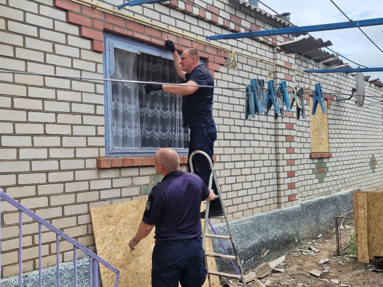 Знімок крупним планом уламків ворожого снаряда чи ракети, які лежать на пожухлій траві та розритій землі. Близько семи обгорілих, деформованих та розірваних металевих осколків сірого й чорного кольорів різної форми та розміру викладені в ряд для фіксації доказів воєнного злочину. На деяких шматках металу видно залишки внутрішнього покриття або маркування.