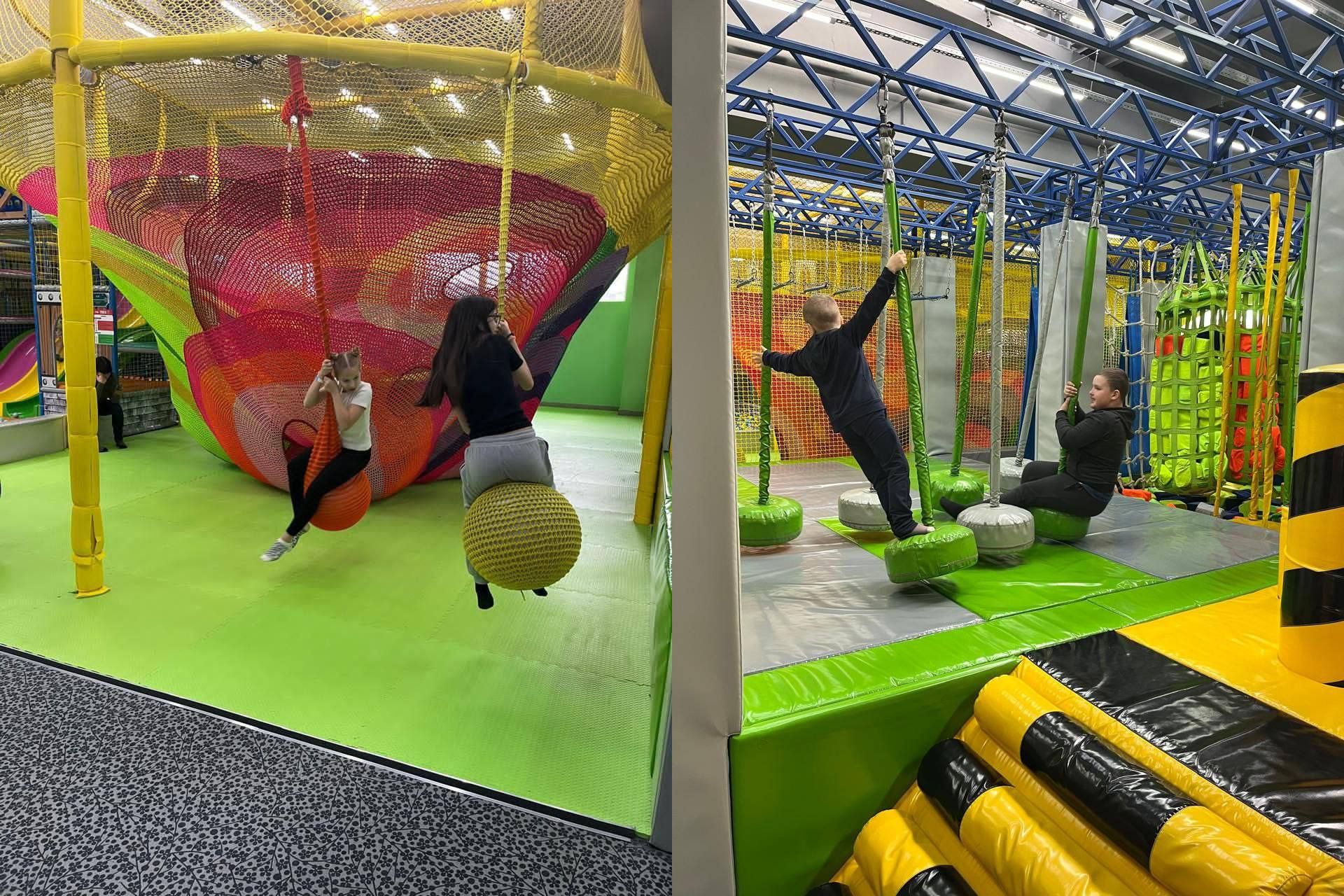 Четверо підлітків розважаються на підвісних гойдалках у великому сучасному дитячо-розважальному комплексі, який має багато різнокольорових сіток та м'яких елементів