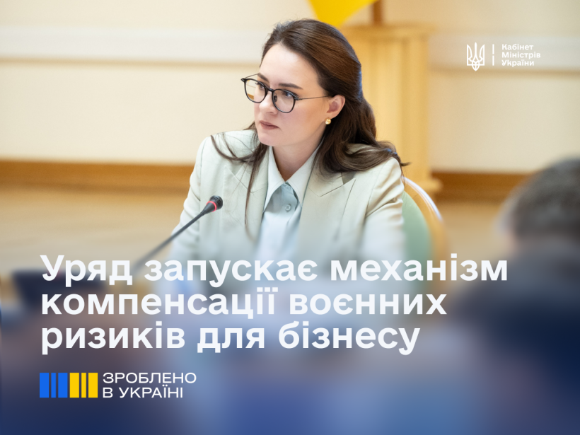 Крупний план жінки в окулярах (Юлія Свириденко), яка сидить за столом на діловій зустрічі. Текст на зображенні: "Уряд запускає механізм компенсації воєнних ризиків для бізнесу.