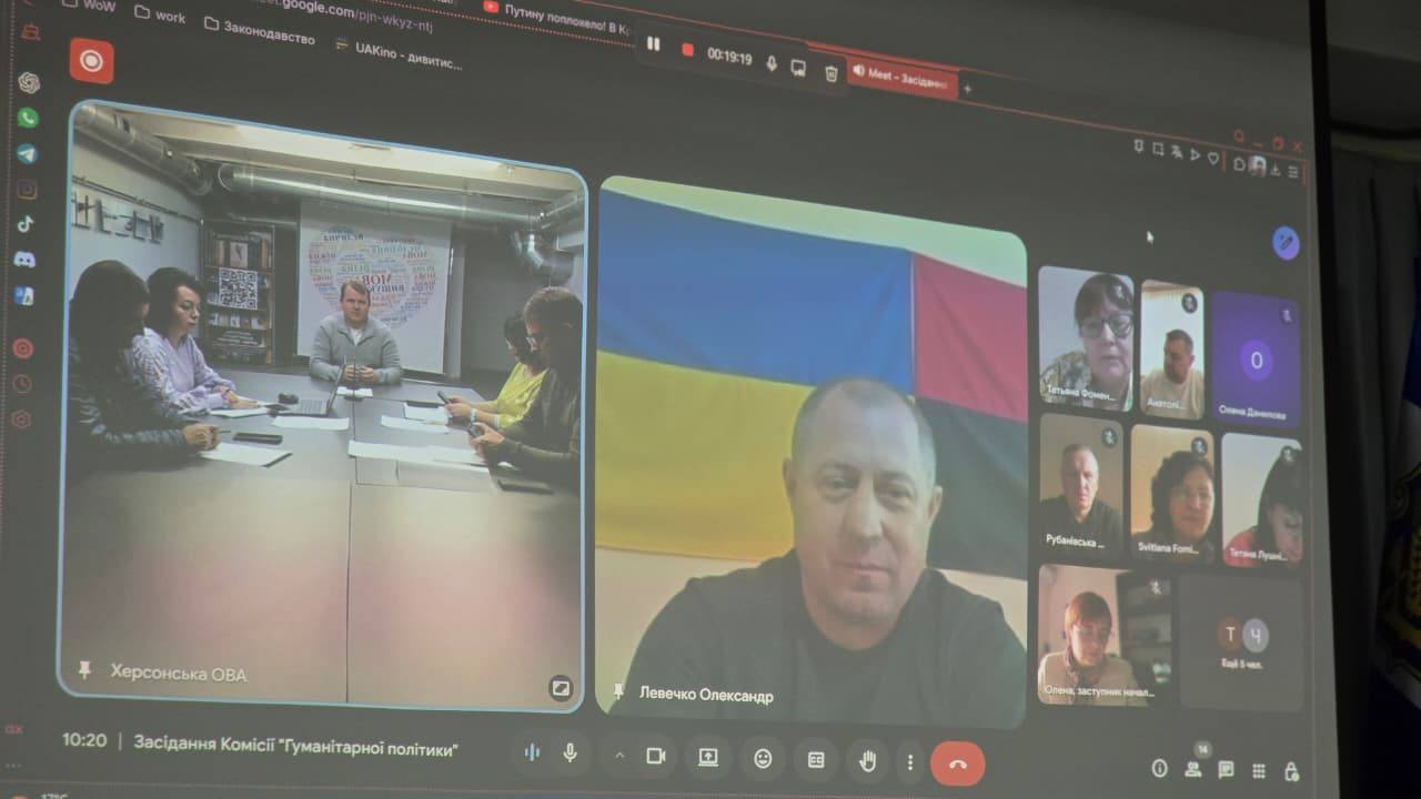 Екран комп'ютера під час онлайн-конференції (відеозустрічі), що називається Засідання Комісії 'Гуманітарної політики. На екрані видно декілька учасників, включаючи велике вікно з чоловіком на тлі прапора та вікно з чотирма учасниками, які сидять за столом (вікно підписане Херсонська ОВА).