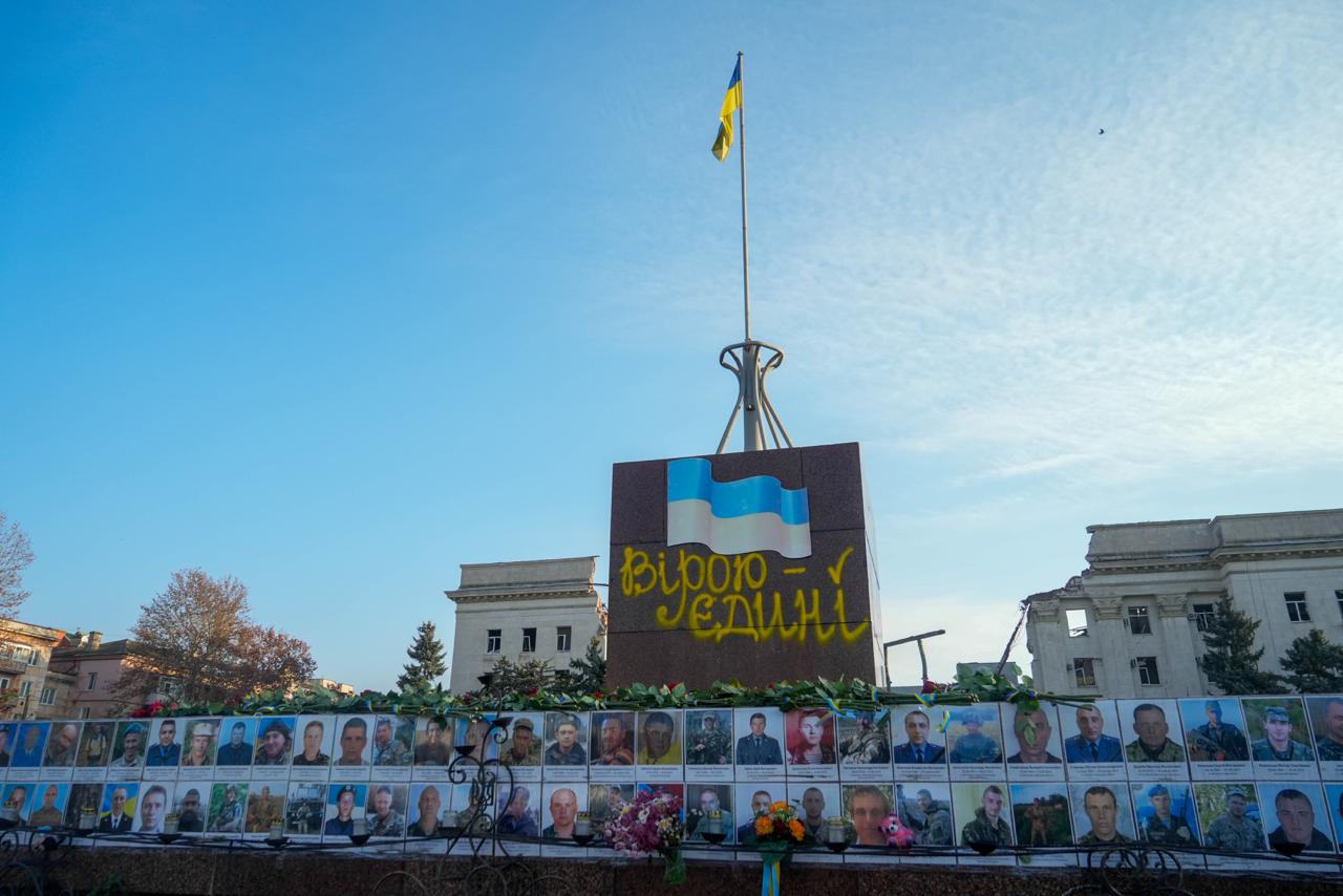 Меморіал загиблим захисникам, де під монументом із написом: Вірою – Єдині і українським прапором розташовані два ряди портретів військовослужбовців.