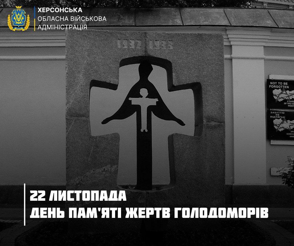 Пам'ятник жертвам Голодоморів у вигляді хреста з фігурою в центрі. Угорі напис: ХЕРСОНСЬКА ОБЛАСНА ВІЙСЬКОВА АДМІНІСТРАЦІЯ, 1932-1933. Внизу великими літерами: 22 ЛИСТОПАДА ДЕНЬ ПАМ'ЯТІ ЖЕРТВ ГОЛОДОМОРІВ.