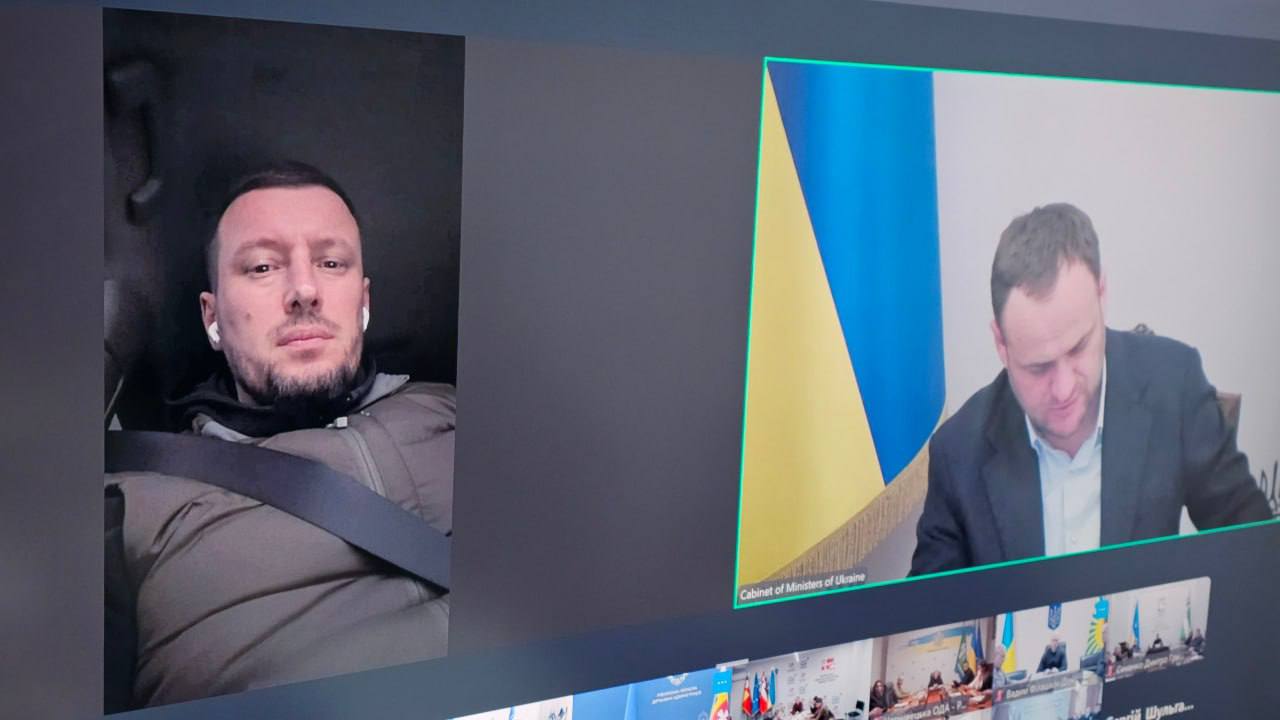 Знімок екрана під час онлайн-наради. Ліворуч — чоловік у навушниках, праворуч — інший учасник на фоні прапора України з написом: Cabinet of Ministers of Ukraine.