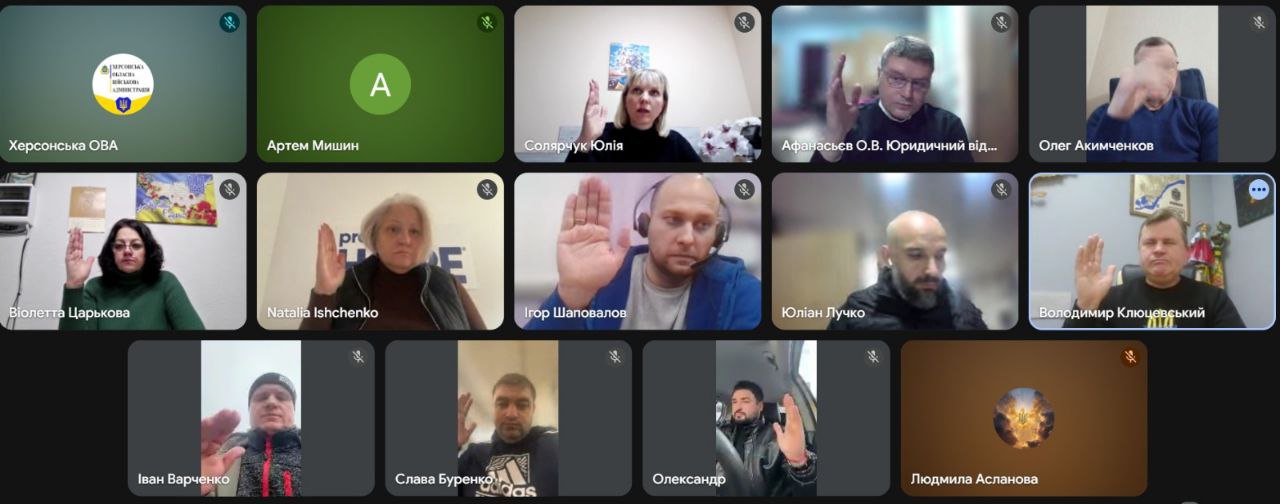 Скриншот онлайн-наради у форматі відеозв'язку, в якій беруть участь представники Херсонської ОВА та інші фахівці. Учасники на екрані одночасно підняли праву руку, що символізує процес голосування або висловлення згоди під час дистанційного засідання.