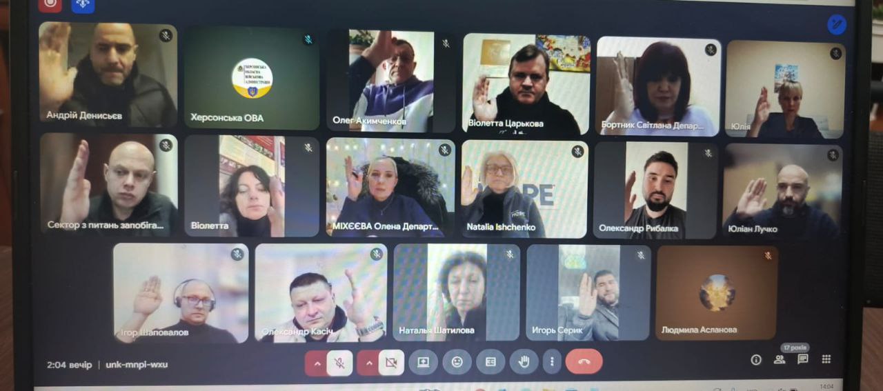 Знімок екрана ноутбука під час онлайн-конференції у Google Meet. На екрані видно вікна з відеоучасниками, більшість із яких підняли руку для голосування або привітання. Один із вікно-слотів містить логотип Херсонської ОВА.