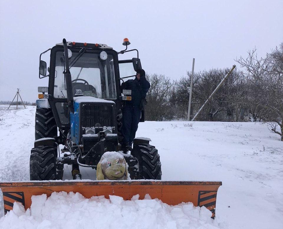  Трактор із відвалом розчищає глибокий сніг на відкритій місцевості в зимовий період.