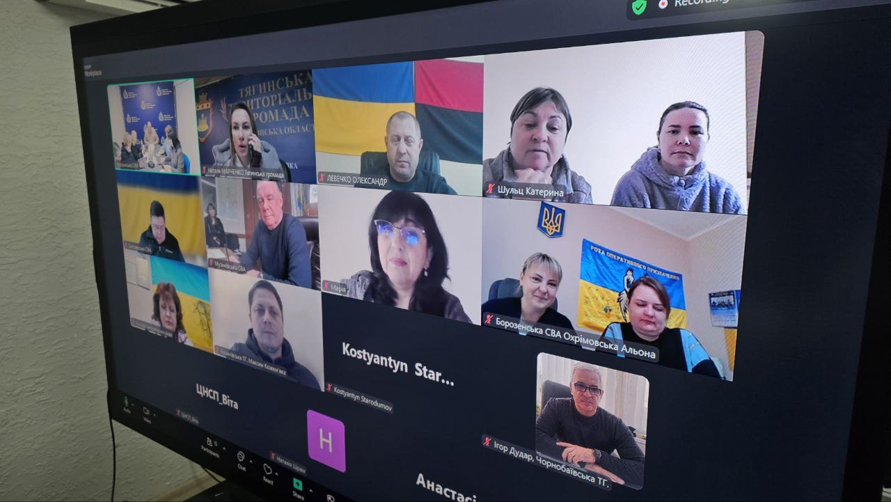 Екран монітора, на якому відображено онлайн-нараду у форматі відеоконференції. У вікнах зв'язку видно учасників зустрічі на фоні українських прапорів та офіційної символіки територіальних громад.