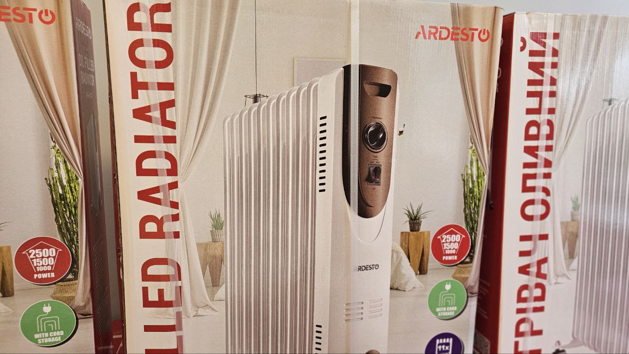 Крупний план картонного пакування оливного радіатора Ardesto. На коробці зображено білий електричний обігрівач та вказано його характеристики, зокрема потужність (2500/1500/1000 Вт) та наявність місця для зберігання шнура. Написи на пакуванні виконані англійською та українською мовами.