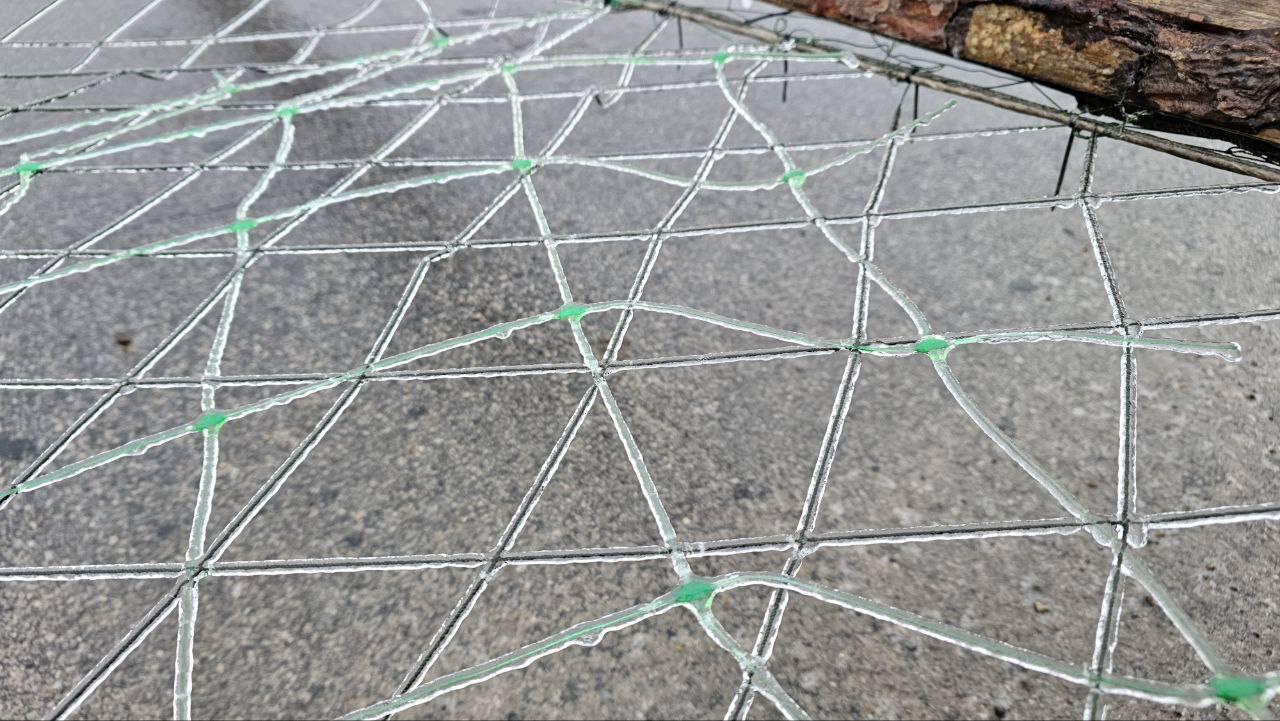 Металева сітка на асфальті, повністю вкрита шаром криги.