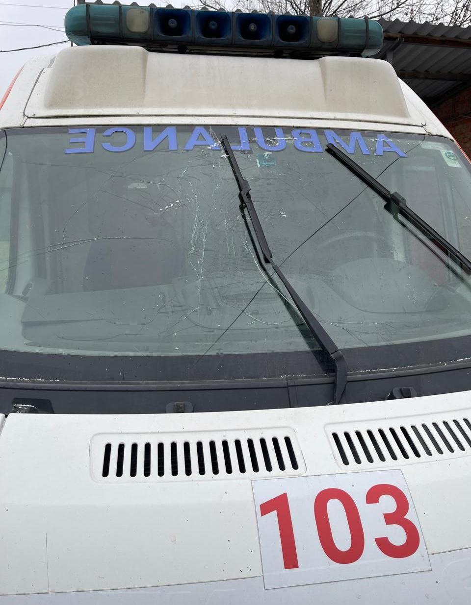 Пошкоджене лобове скло автомобіля швидкої допомоги з тріщинами від ударів, на капоті видно номер "103".