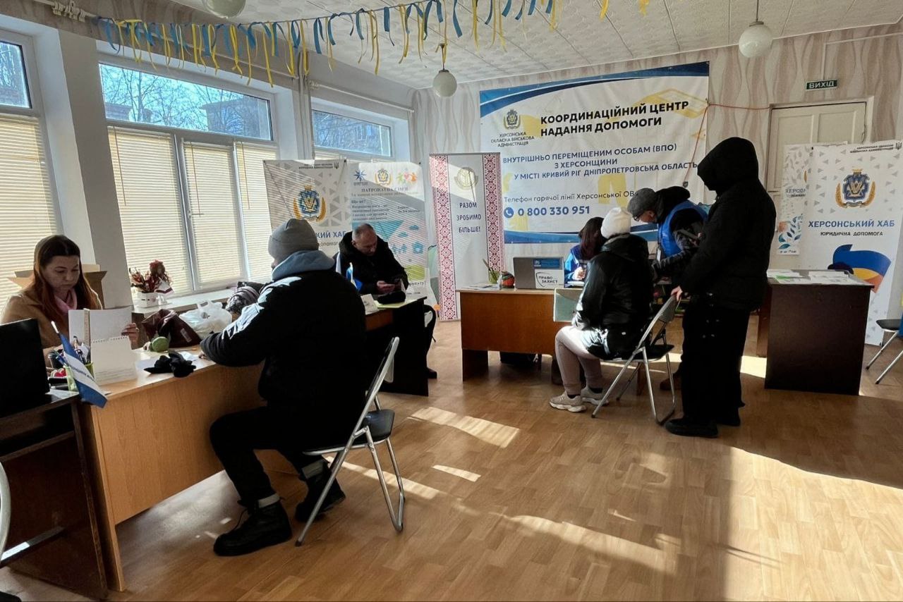 Приміщення гуманітарного хабу, де працівники за столами консультують відвідувачів. На стіні розміщено банер «Координаційний центр надання допомоги внутрішньо переміщеним особам з Херсонщини.
