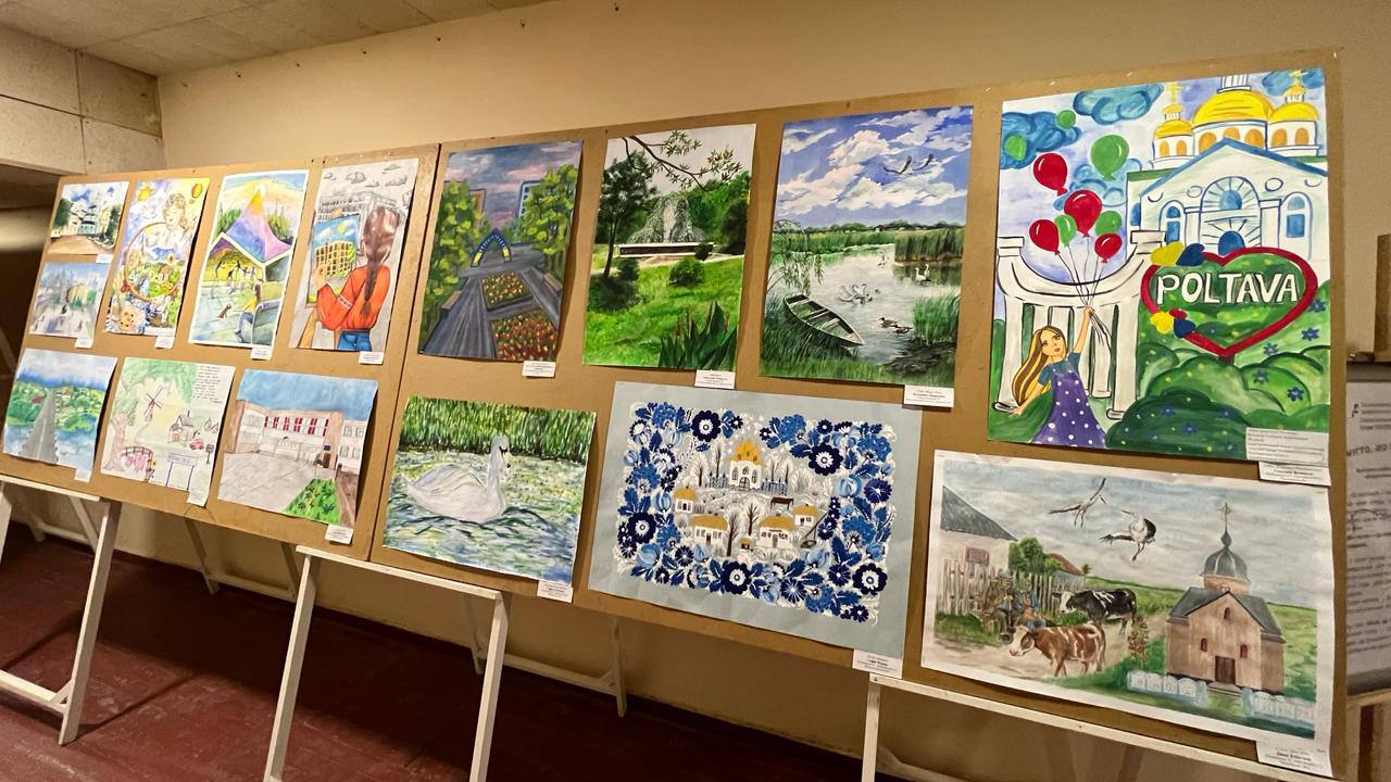 Виставка дитячих малюнків на великих стендах у приміщенні. Роботи виконані в різних техніках і зображують пейзажі, архітектуру Полтави, патріотичні сюжети та природу. Кожен малюнок має невелику підписну табличку.