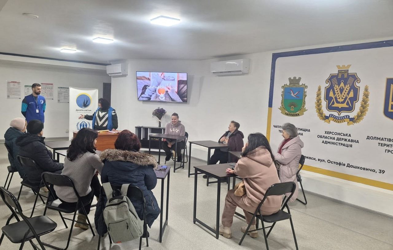 Загальний план заняття в залі з інформаційним банером Херсонської ОДА на стіні.