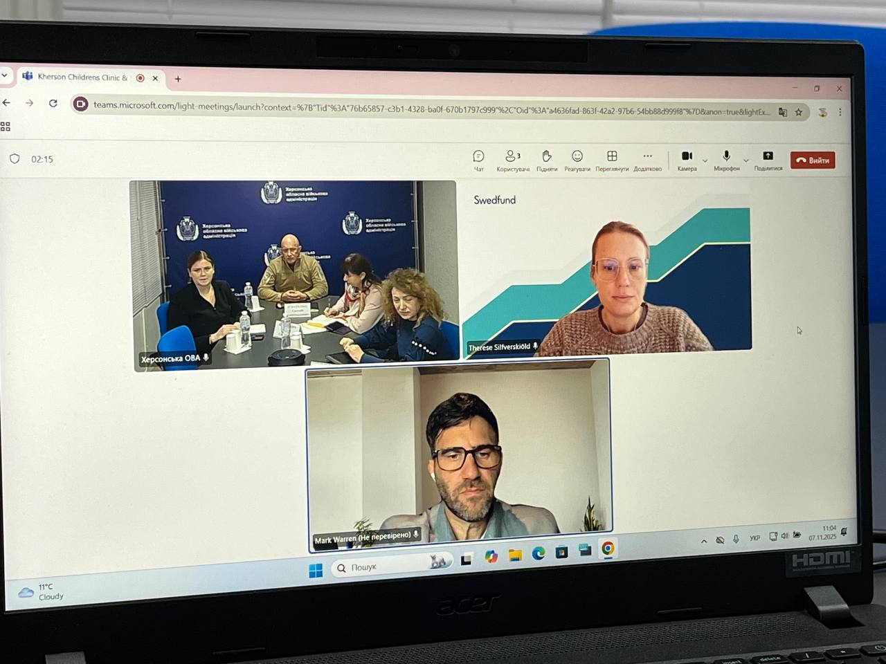 Екран ноутбука з відкритою відеоконференцією Microsoft Teams. На екрані видно чотири вікна з учасниками: у верхньому лівому куті – групова зустріч, підписана Херсонська ОВА, у верхньому правому – жінка і в нижньому – чоловік.