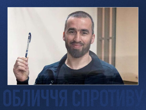 Усміхнений чоловік з бородою та коротким волоссям тримає в руці вгору синю кулькову ручку. Його знімок зроблено на світлому фоні. Унизу синім кольором частково видно текст ОБЛИЧЧЯ СПРОТИВУ.